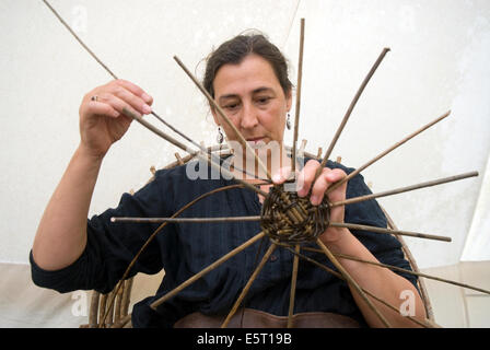 Femme tissant la base d'un panier tressé à un pays jeux et foire artisanale, selborne, Hampshire, Royaume-Uni. Banque D'Images