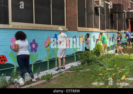 Les bénévoles Touch-up une murale sur le côté une école dans le quartier de Chelsea, New York Banque D'Images