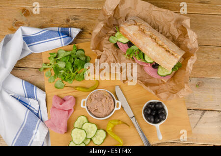 Baguette méditerranéen avec des ingrédients sur planche à découper en bois Banque D'Images