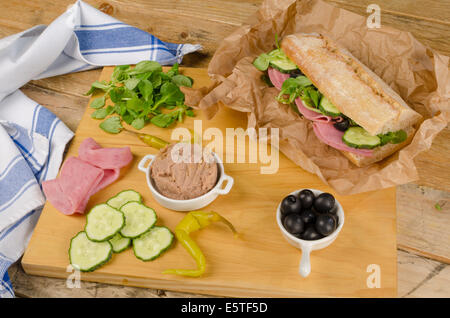 Baguette méditerranéen avec des ingrédients sur planche à découper en bois Banque D'Images