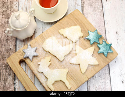 Biscuit sablé de Noël Maison cookies dans rennes et formes festives avec une tasse de thé sur vintage shabby bleu et blanc Banque D'Images