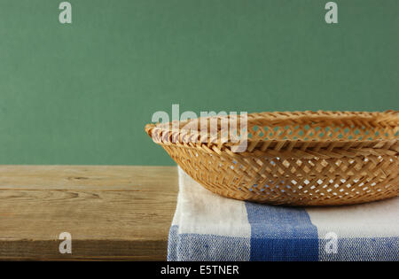 Panier en osier vide sur une vieille table en bois contre mur grunge Banque D'Images