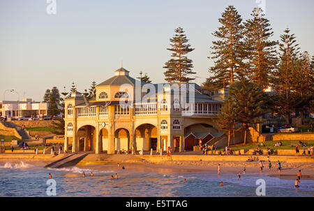 Les nageurs se détendre et se baigner au coucher du soleil en face de l'emblématique vieux pavilion at Cottesloe Beach à Perth, Australie occidentale. Banque D'Images