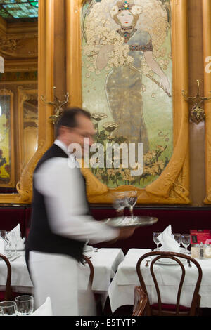 Serveur français transportant un plateau de verres de vin dans la Brasserie Julien le style Art Nouveau à Paris. Banque D'Images