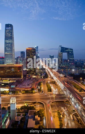 Belle vue panoramique sur la ville de la capitale chinoise et le célèbre monument du siège de CCTV, avec les lumières de la circulation sur le troisième périphérique et les bureaux et les bâtiments éclairant la scène en début de soirée. Rare scène panoramique pendant l'heure bleue juste après le coucher du soleil avec un ciel clair à Guomao, le quartier central des affaires de Beijing, situé dans le quartier de Chaoyang, Chine, RPC. © Olli Geibel Banque D'Images