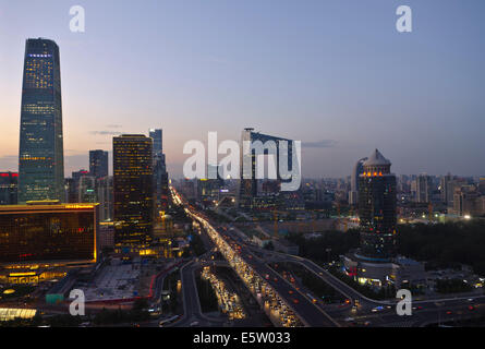 Belle vue panoramique sur la ville de la capitale chinoise et le célèbre monument du siège de CCTV, avec les lumières de la circulation sur le troisième périphérique et les bureaux et les bâtiments éclairant la scène en début de soirée. Rare scène panoramique pendant l'heure bleue juste après le coucher du soleil avec un ciel clair à Guomao, le quartier central des affaires de Beijing, situé dans le quartier de Chaoyang, Chine, RPC. © Olli Geibel Banque D'Images