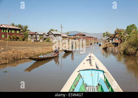 Les gens l'aviron canoës en bois le long d'un canal dans un village près de Lac Inle, Shan, Myanmar Banque D'Images