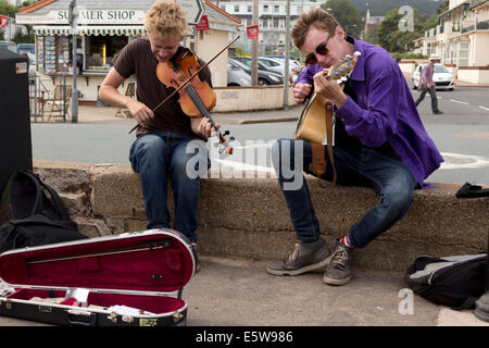 Les amuseurs publics jouant du violon et de la guitare sur promenade à Sidmouth Folk Festival 2014. Banque D'Images