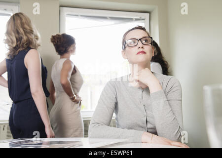 Young businesswoman le regard tandis que ses collègues donnent de la fenêtre Banque D'Images