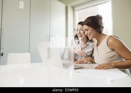 Deux businesswoman laughing and looking at laptop Banque D'Images