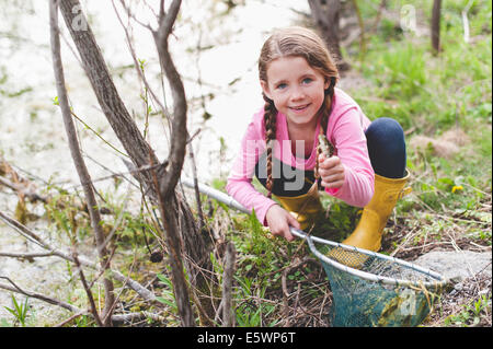 Portrait of Girl holding up frog et filet de pêche Banque D'Images