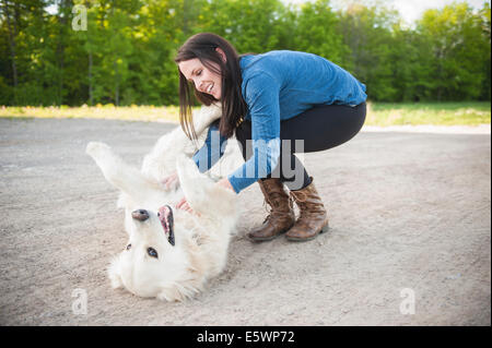 Young woman petting golden retriever sur route Banque D'Images