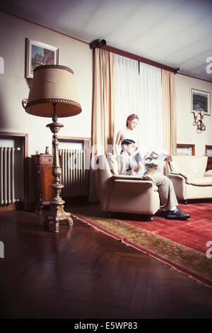 Portrait of young couple vintage dans la salle de séjour reading newspaper Banque D'Images