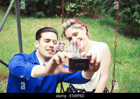 Jeune couple vintage camera selfies dans jardin Banque D'Images