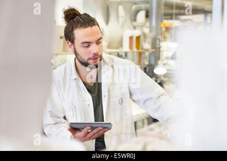 Potter mâle using digital tablet in atelier de céramique