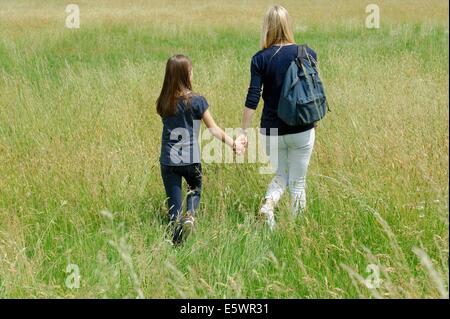 Vue arrière de la mère et la fille se baladant dans la longue herbe domaine Banque D'Images