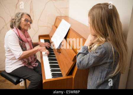 Petite-fille regardant grand-mère joue du piano Banque D'Images