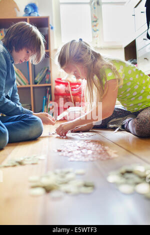 Frère et sœur à compter des pièces de savings jar Banque D'Images