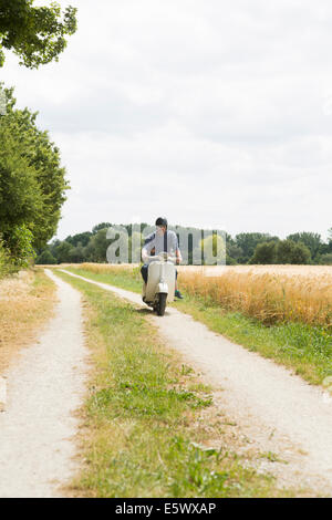 Man riding scooter le long chemin avec fille tenant à la taille Banque D'Images