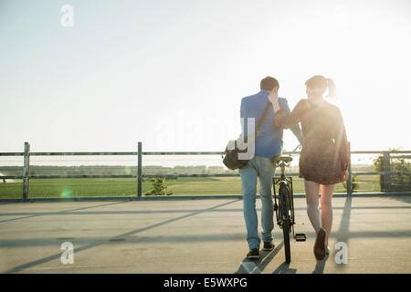 Jeune couple poussant en vélo parking vide Banque D'Images