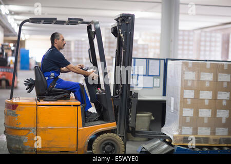 Homme mûr à l'aide de chariot élévateur en usine Banque D'Images