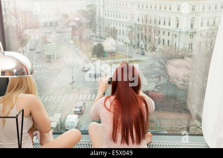 Young woman taking photograph par fenêtre d'hôtel avec vue, Vienne, Autriche Banque D'Images