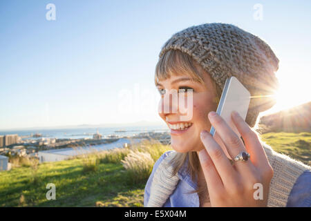 Young woman chatting on smartphone, vue sur le port en arrière-plan, Le Cap, Afrique du Sud Banque D'Images