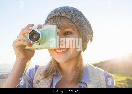 Young woman taking photograph avec l'appareil photo au coucher du soleil Banque D'Images