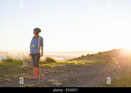 Young woman standing on hill au coucher du soleil Banque D'Images