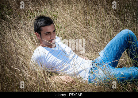 Portrait de jeune homme confortablement assis dans l'herbe haute Banque D'Images