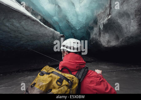 Man crossing river avec une corde dans la caverne de glace, glacier de Vatnajokull, Parc national du Vatnajökull, Islande Banque D'Images