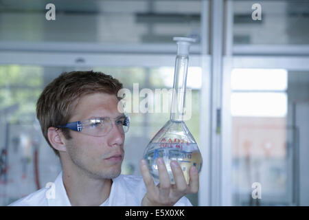 Young male scientist holding fiole jusqu'au laboratoire Banque D'Images