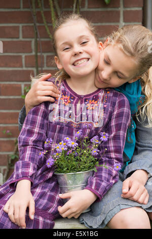 Deux soeurs avec pot de fleur plante dans jardin Banque D'Images