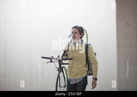 Mid adult man carrying bicycle par passage souterrain de la ville Banque D'Images