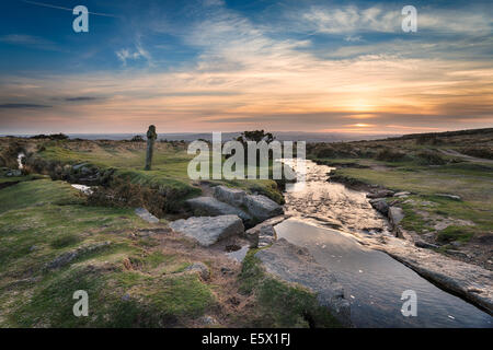 Coucher du soleil à Windy Publiez une ancienne croix de granit aux côtés le Beckamoor Brook comme il traverse le Sortridge Grimstone et L Banque D'Images