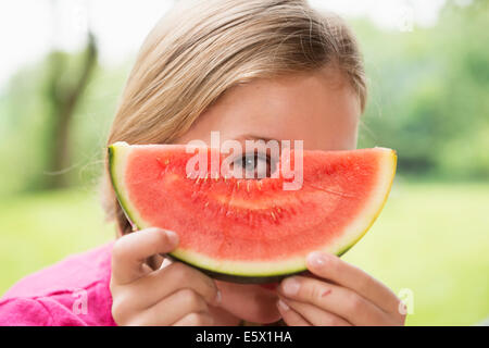 Close up portrait of girl peering through watermelon slice Banque D'Images