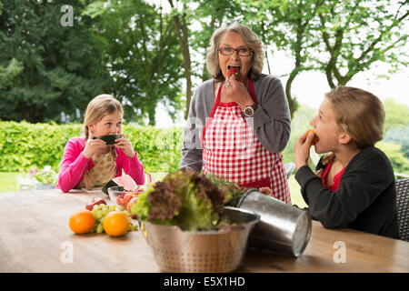 Deux sœurs et une grand-mère à manger des fruits de table de patio Banque D'Images