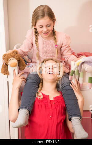 Girl laughing tout en donnant une épaule soeur ride dans la chambre Banque D'Images