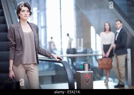 Young businesswoman with briefcase sur escalator dans conference centre Banque D'Images