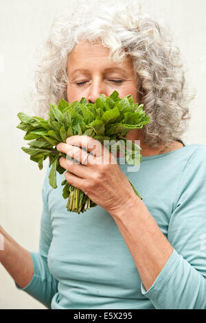 Young woman smelling bouquet de menthe dans le jardin Banque D'Images