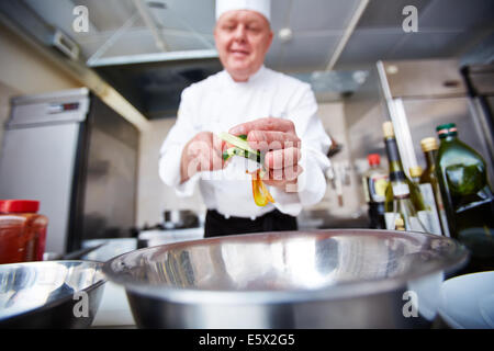 Image de l'homme chef putting couper les légumes dans le bol dans la cuisine Banque D'Images