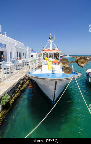 Bateau de pêche à côté de tables le long du bord de Naoussa, Paros, Cyclades, Grèce Banque D'Images