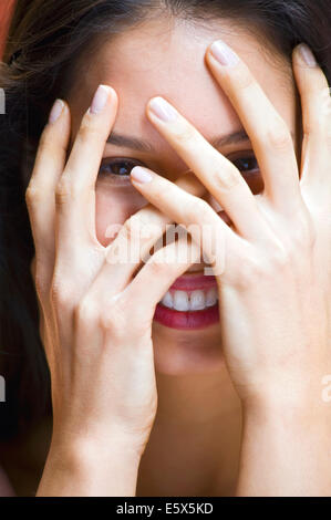 Portrait of young woman with hands covering face Banque D'Images