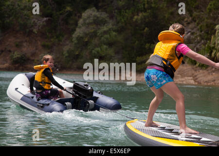 Frère en canot à moteur sur le paddleboard permanent soeur de remorquage Banque D'Images