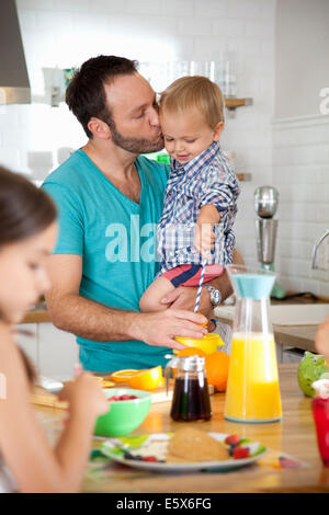 Mid adult man multi tasking petit-déjeuner avec son fils et sa fille Banque D'Images