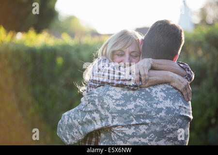 Soldier hugging mère sur rue à homecoming Banque D'Images