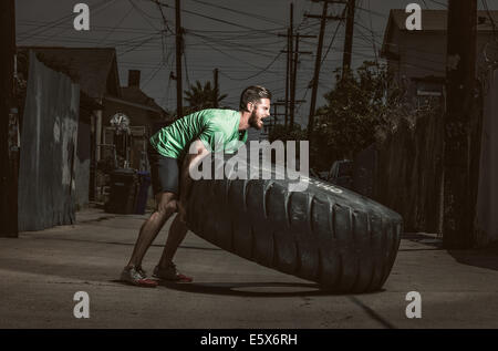 Young adult man lifting des pneus Banque D'Images