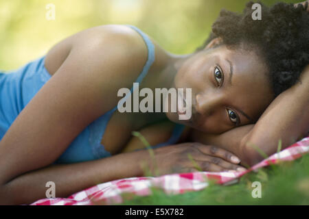 Portrait of young woman lying on side in park Banque D'Images