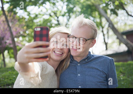 Young couple in park en tenant avec smartphone selfies Banque D'Images