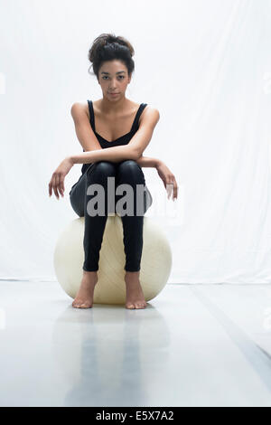 Studio portrait of young woman sitting on exercise ball